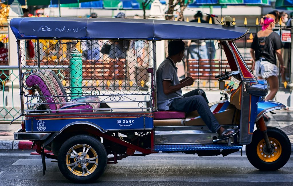 a man sitting on the back of a blue three wheeled vehicle